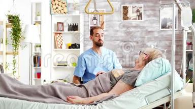 一位男医生和躺在养老院病床上的生病的老太太谈话
